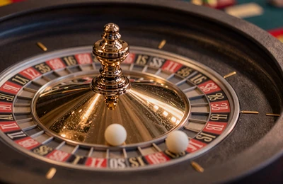 Poliertes Roulette-Rad mit wei&szlig;er Kugel w&auml;hrend der Drehung im goldenen Licht