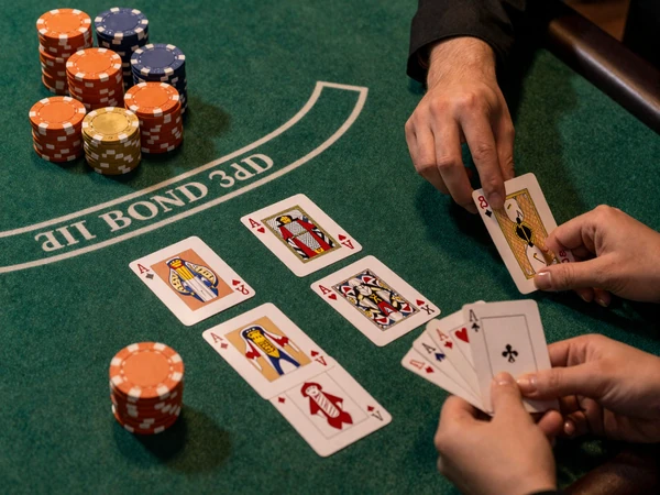 Black Jack-Tisch mit gr&uuml;nem Filz, ausgeteilten Karten mit 21 und orangen Casino-Chips von oben